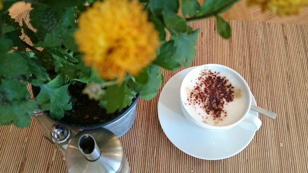 Tasse Cappuccino mit Blumen auf den Tisch. Moment der Muße am #WMDEDGT