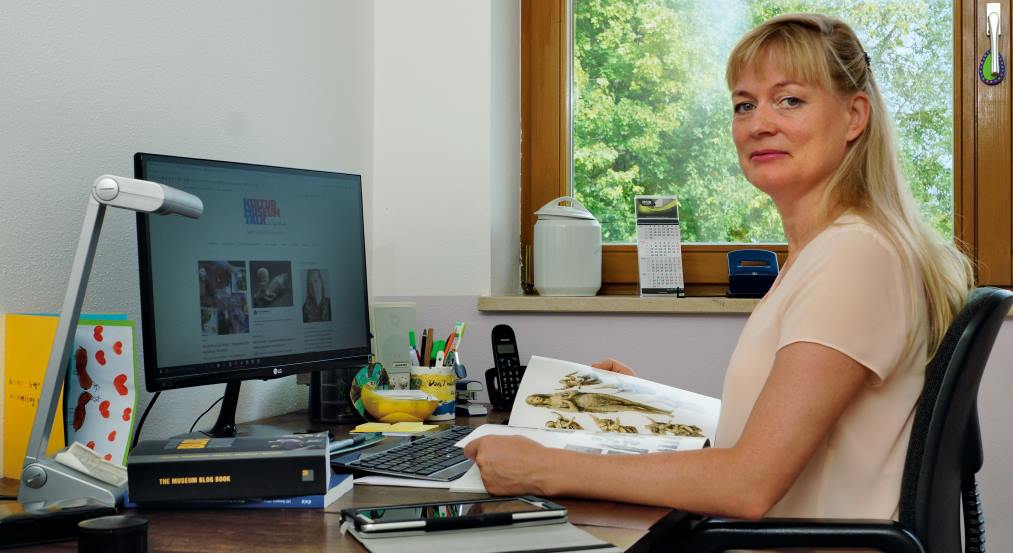 Die Kunsthistorikerin und Kulturbloggerin Tanja Praske bei der Arbeit am Schreibtisch mit Katalog, Büchern und Tablet.